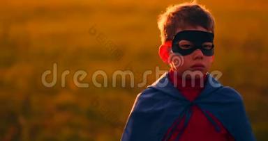 一个戴着面具的男孩和一个<strong>超级</strong>英雄在<strong>日</strong>落时在田野里的斗篷